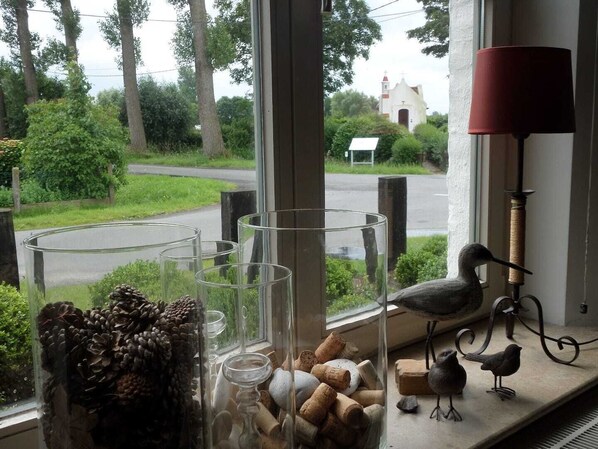A window with a view of a road, a church, and a lamp.