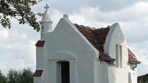 Une petite église blanche, avec un toit recouvert de tuiles rouges et une croix au sommet.