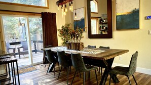 A dining area with a wooden table, six chairs, a vase of flowers, and a large mirror on the wall. - Cozy Tahoe Donner Retreat – Hot Tub, Fireplace & Near Ski Resorts! (Truckee)