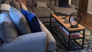 Una sala de estar con un sofá modular, una mesa de centro y una puerta decorada con objetos colgantes.