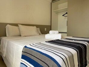 Une chambre d’hôtel avec un lit, une table de chevet, un miroir et un porte-manteau mural.