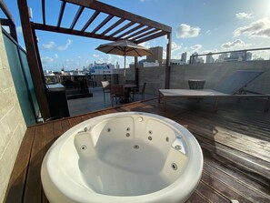 Une terrasse sur le toit dotée d’un jacuzzi, de mobilier d’extérieur et offrant une vue sur le panorama urbain.