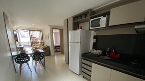 A kitchen with a refrigerator, microwave, and black countertop. - Bela Hospedagem-EcoSummer Duplex Tambaú (João Pessoa)