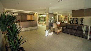 A modern lobby with a reception desk, seating area, and potted plants. - Bela Hospedagem-EcoSummer Duplex Tambaú (João Pessoa)