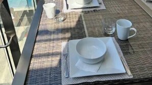 A balcony with a table set for two, including plates, bowls, and cups. - Luxurious 1 bedroom condo. On the South (Kingston)