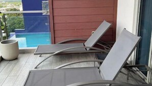 A balcony with two reclining lounge chairs and a potted plant. - Luxurious 1 bedroom condo. On the South (Kingston)