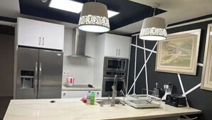 A modern kitchen with a central island, stainless steel appliances, and black chairs around the island. - Luxurious 1 bedroom condo. On the South (Kingston)