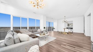 A spacious living room with a large sofa, coffee table, and a chandelier.