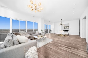 A spacious living room with a large sofa, coffee table, and a chandelier.