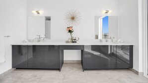 A modern bathroom with two sinks, dark cabinets, and a decorative mirror.