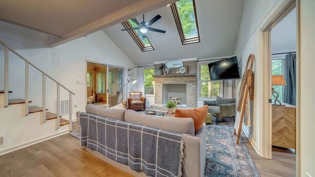 A spacious living area with a sofa, TV, fireplace, and a ceiling fan. - Secluded Retreat w Hot Tub, FirePit & Pool Access (Hedgesville)
