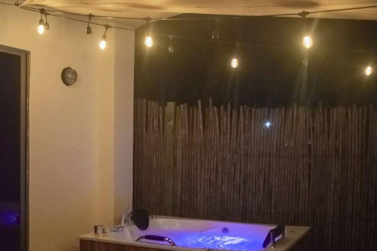 Een gezellig interieur met een houten tafel en stoelen, een jacuzzi en lichtjes.