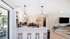 A modern kitchen with a large island, bar stools, pendant lighting, and a dining area with a bench. - ☆New☆6min to 3 Sisters Springs☆Spacious, Fun with Game room (Crystal River)