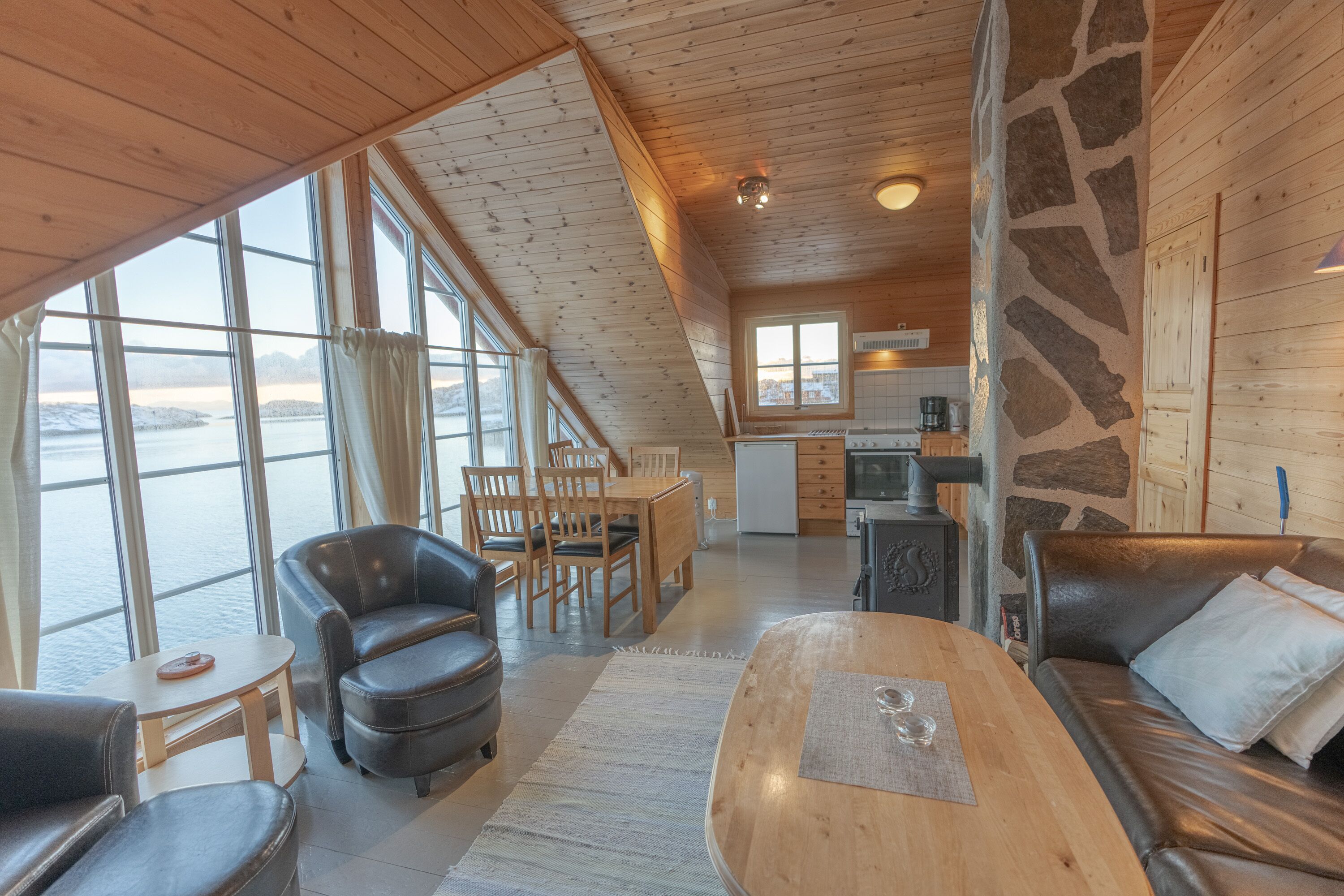 A cozy cabin interior with a dining area, a sofa, and a kitchen.