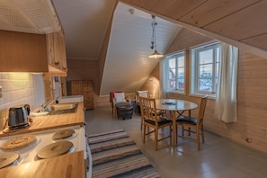 A cozy kitchen with wooden cabinets, a stove, and a dining area with chairs and a table.