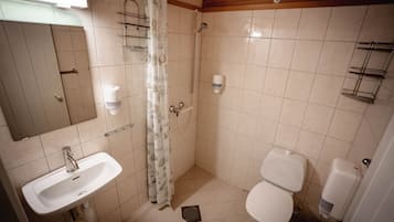 Un baño con lavamanos, inodoro, ducha y espejo.