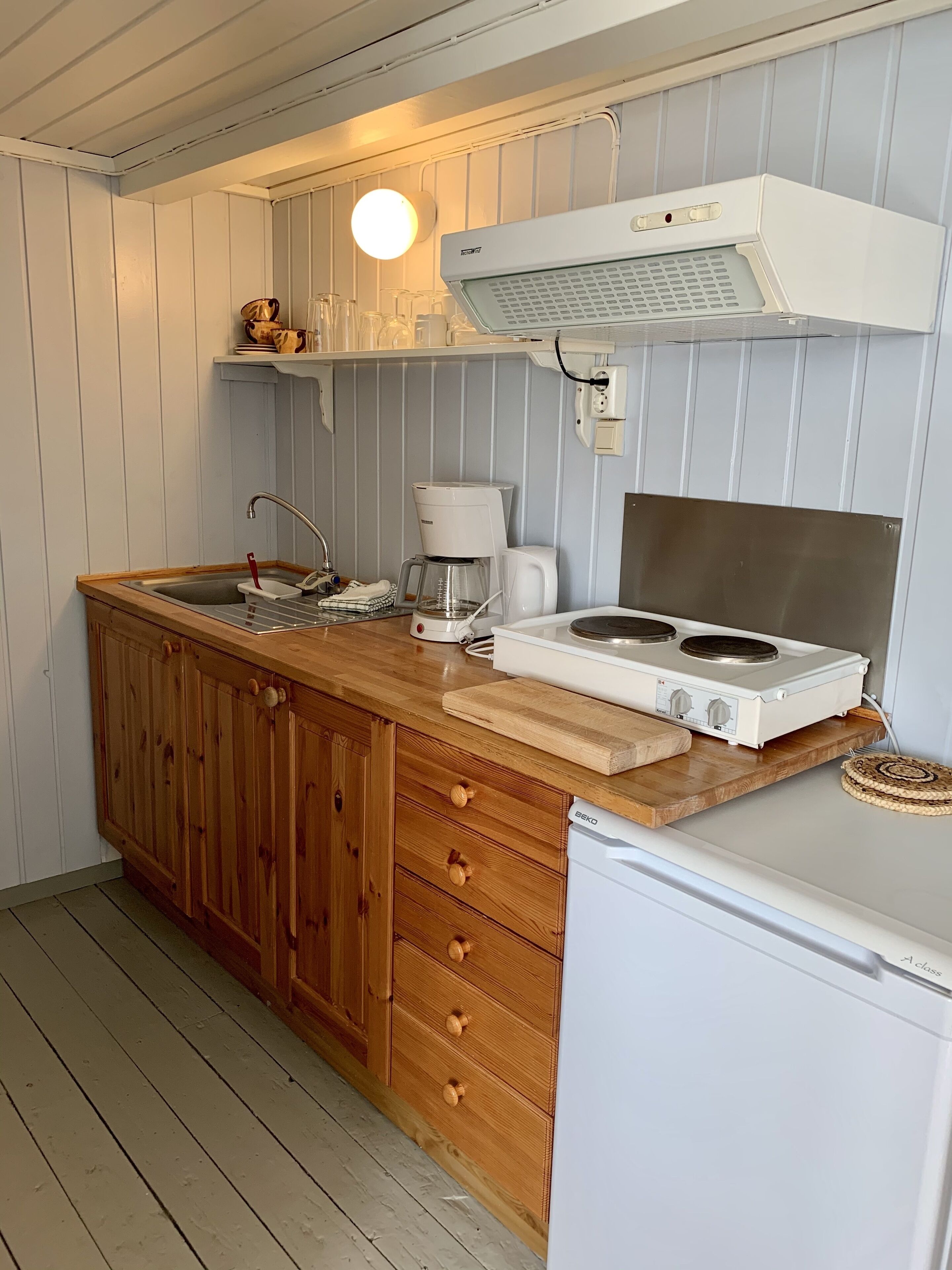 A compact kitchen with wooden cabinets, a built-in stove, and a coffee maker.