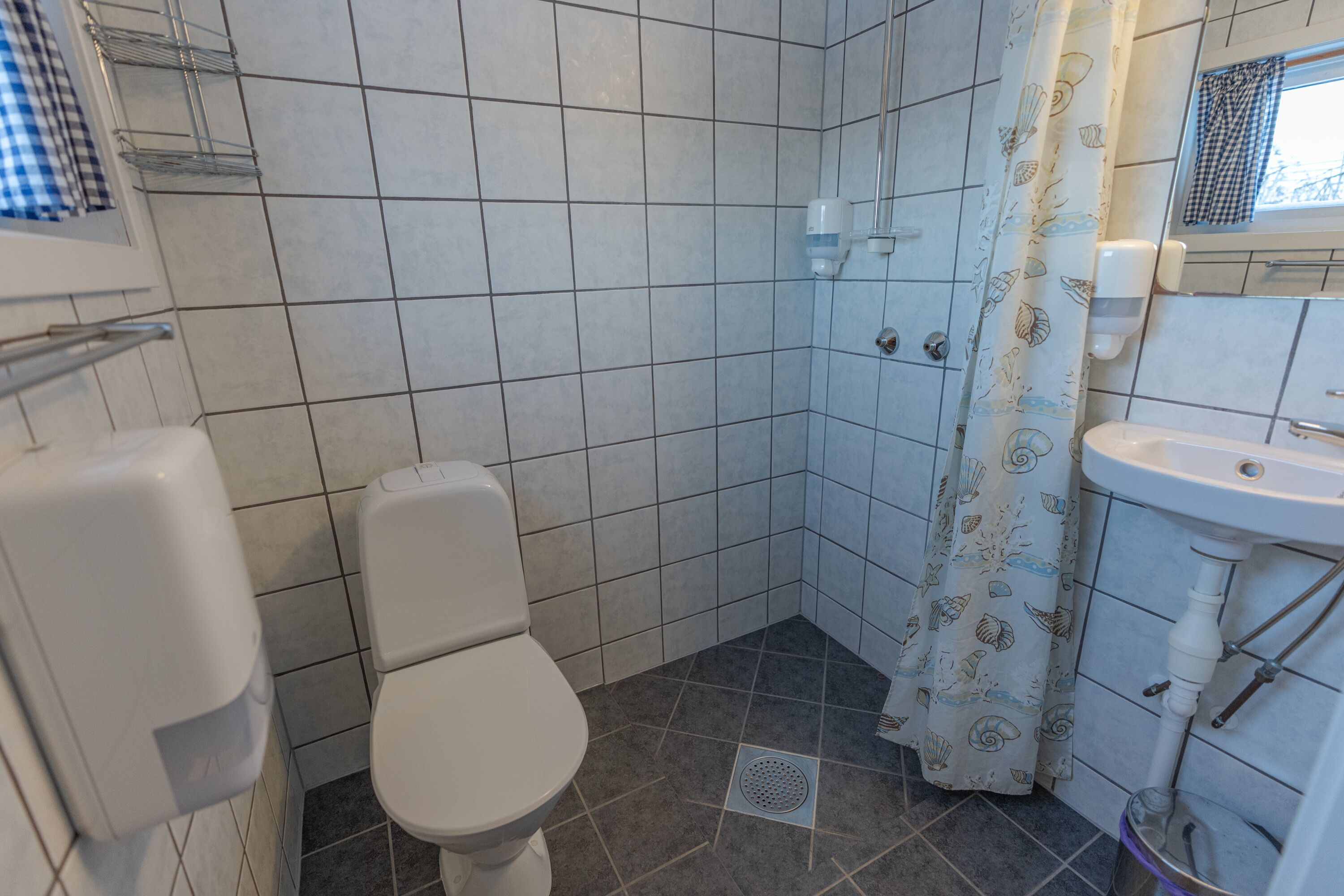 A bathroom with a toilet, a sink, a shower, and a hand dryer.