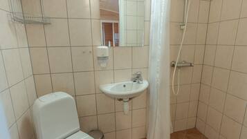 Pieni kylpyhuone, jossa on wc, pesuallas ja suihku.