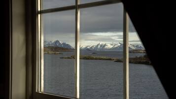 A window with a view of a fjord and mountains.