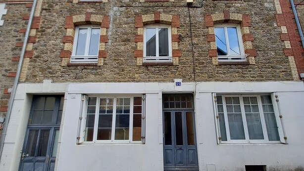 Un immeuble à plusieurs étages, doté d’une façade en pierre, de nombreuses fenêtres et d’un toit plat.