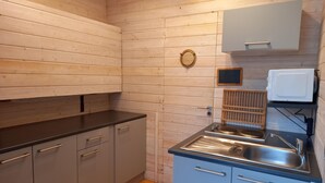 Une cuisine de taille réduite avec des murs en bois, un plan de travail noir et des placards gris.