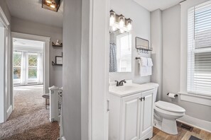 A bathroom with a white vanity, a toilet, and a shower area. - *BRAND NEW* The Frances Rose | Hocking Hills Luxury | Family Friendly! (Logan)