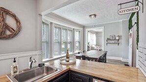 Een moderne keuken met een houten aanrecht, een roestvrijstalen spoelbak en een wijnfles op het aanrecht.