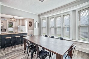 A modern kitchen with a dining area, large windows, and a kitchen sign. - *BRAND NEW* The Frances Rose | Hocking Hills Luxury | Family Friendly! (Logan)