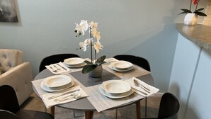 A dining table set with plates, cutlery, and a vase of white flowers. - Downtown two story penthouse  (Seattle)