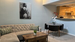 A living room with a sectional sofa, a coffee table, and a dining area with a table and chairs. - Downtown two story penthouse  (Seattle)
