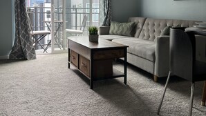 A modern living room with a sofa, a coffee table, and a chair. There is a balcony with a view of the cityscape. - Downtown two story penthouse  (Seattle)