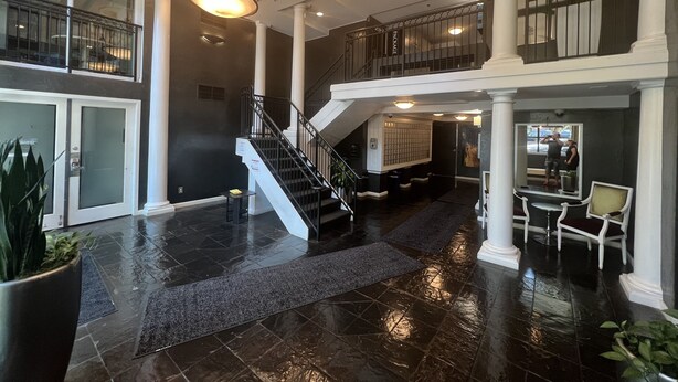 A spacious lobby with a central staircase, a reception desk, and a seating area. - Downtown two story penthouse  (Seattle)
