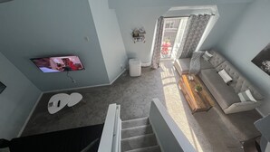 A living room with a TV, a sofa, a coffee table, and a staircase. - Downtown two story penthouse  (Seattle)