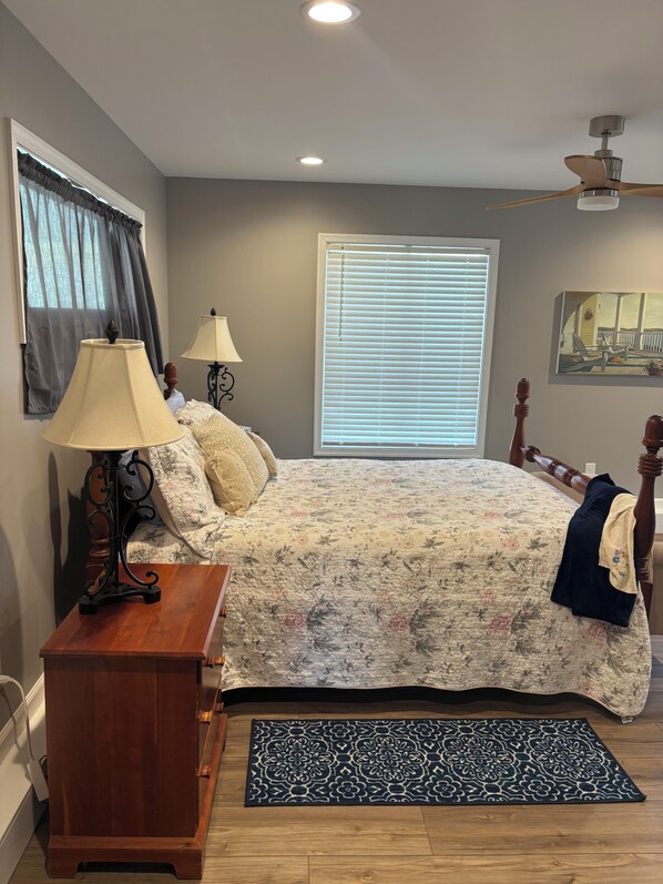 A bedroom with a bed, bedside lamps, a ceiling fan, a window with blinds, and a rug. - Bright, Beautiful Smith Mountain Lakefront, Full Amenities & Perfect Location! (Moneta)