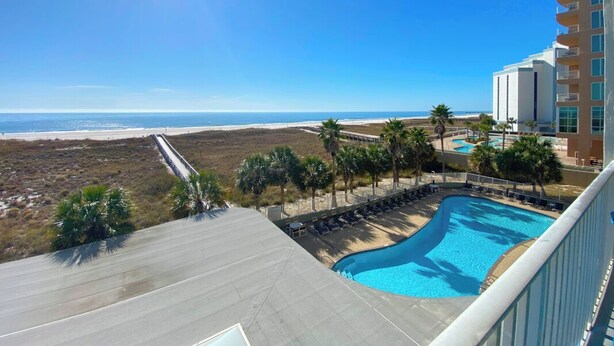 A hotel with a pool, a beach view, and a clear sky.