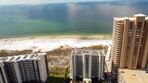 A high-rise hotel overlooking a beach with a clear view of the ocean.