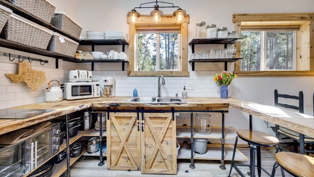 A kitchen with wooden shelves, a large island, and a window with a view of trees. - 13 Mi to USAFA: Peaceful Colorado Springs Getaway! (Colorado Springs)