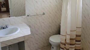 Um banheiro com pia branca, vaso sanitário e cortina de chuveiro.