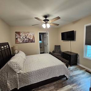 A bedroom with a bed, a ceiling fan, a TV, and a door leading to another room. - Old Made New-3 Bedroom Lovely Home-Dog Friendly (Hendersonville)