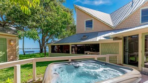 A hot tub in a backyard with a house and a view of the water. - The Roosevelt Suite (2 BEDROOMS/2 BATHS) (Stuart)