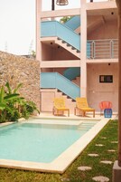 Un edificio moderno con piscina, dos sillones de madera y una escalera.