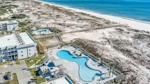 Vista aérea de um resort com piscina, acesso à praia e um edifício grande.