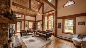 Un salon spacieux doté de parquets en bois, d’une cheminée et de grandes fenêtres.