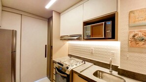 A compact kitchen with a microwave, gas stove, and stainless steel refrigerator. - Lindos apartamentos no Eco Resort (Tamandaré)