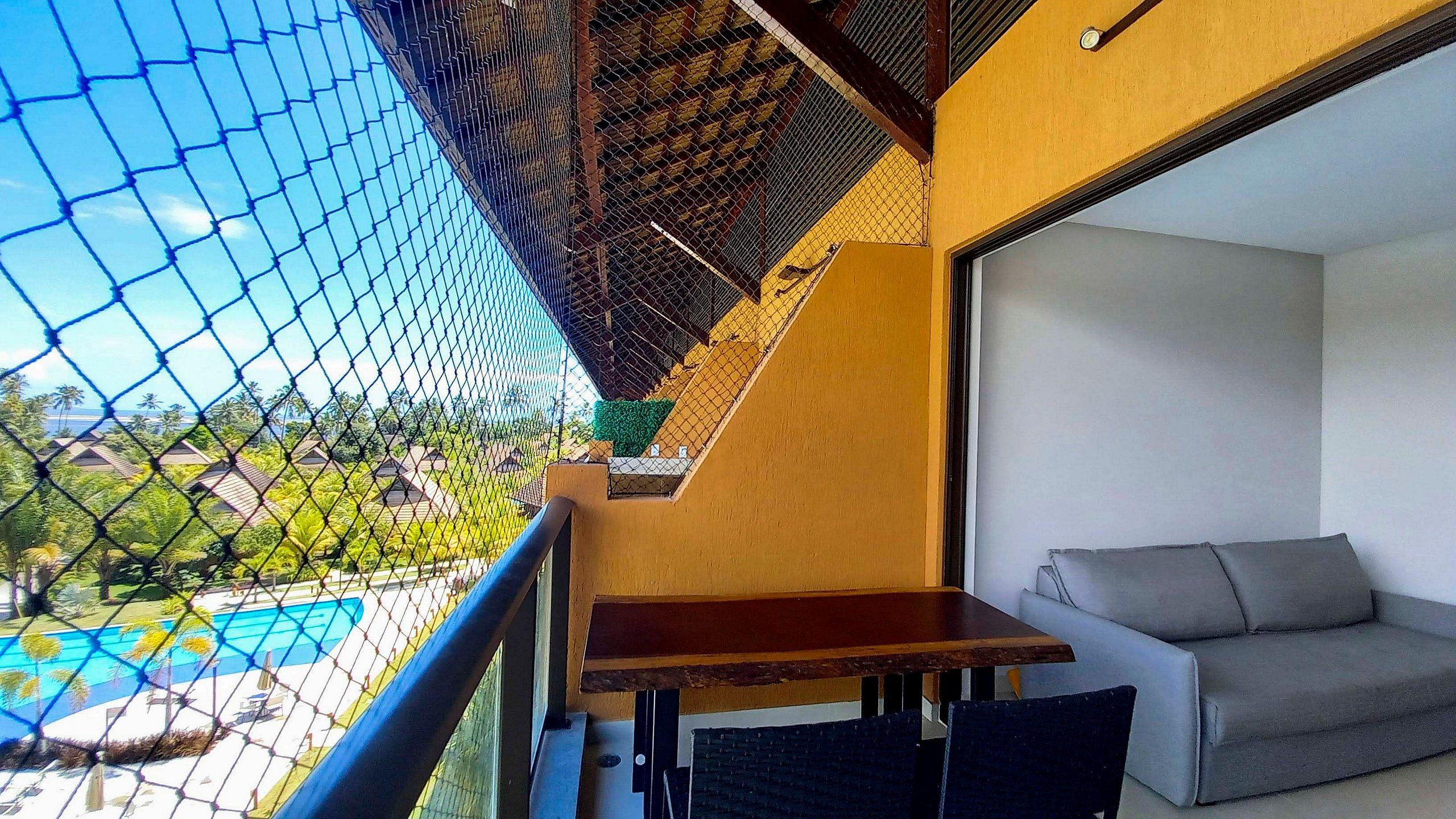 A balcony with a pool view, a table, and a sofa.