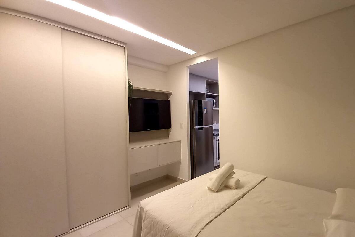 A hotel room with a bed, a TV, a wardrobe, and a small kitchenette.