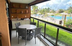 A balcony with a view of a pool and tropical landscape.