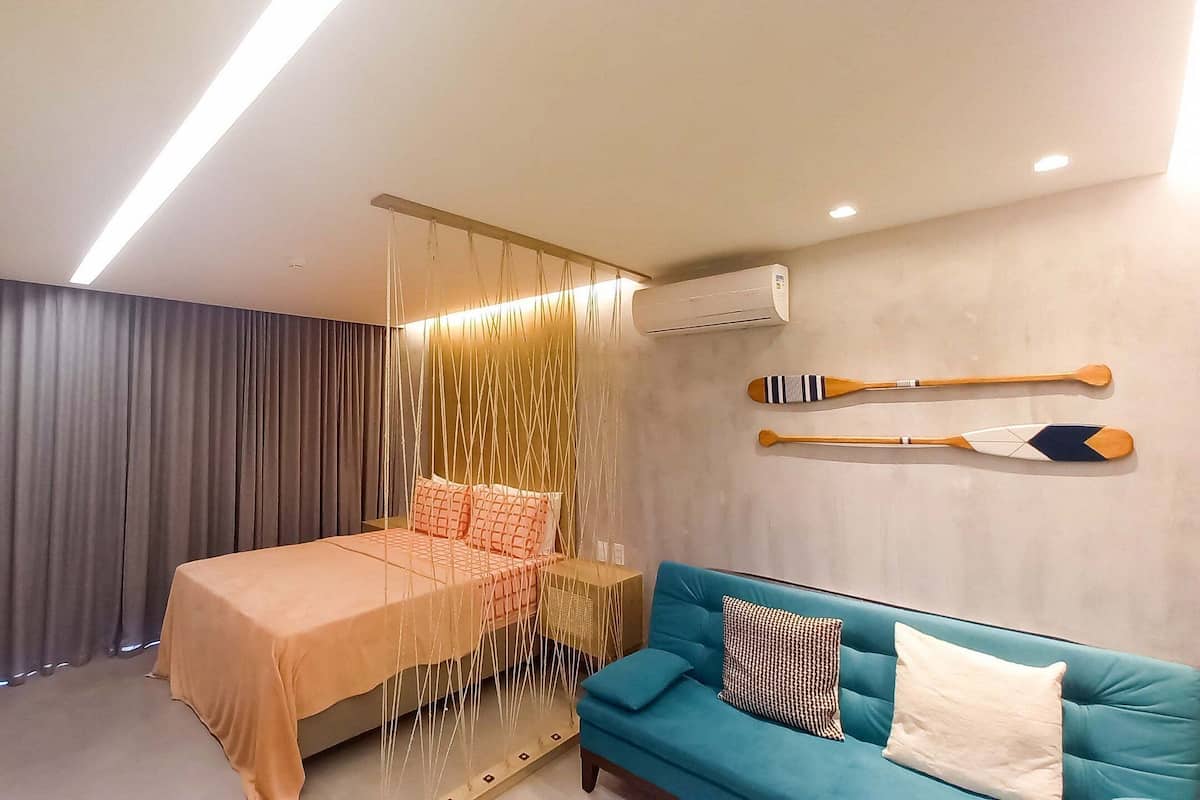 A bedroom with a bed, a blue sofa, and two wooden paddles on the wall.