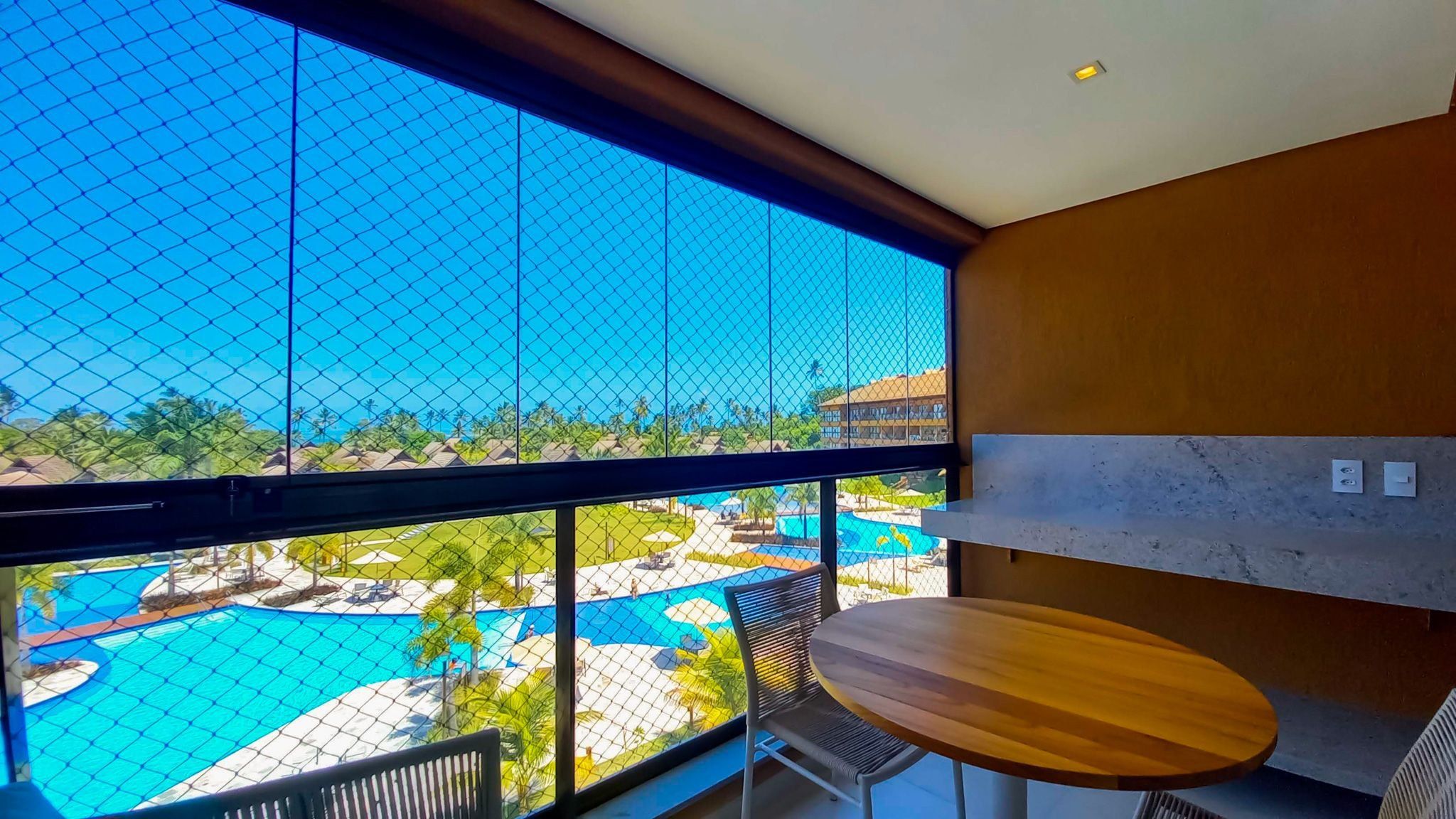 A room with a large window overlooking a pool and resort area.